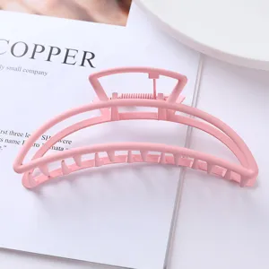 Detail shot of pink metal hair claw clip, elegant geometric arch design for stylish updos.