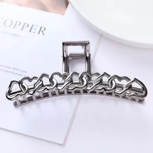 Detailed shot of gunmetal metallic hair claw featuring interlocking openwork heart design.