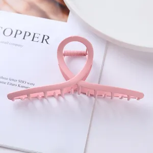 Detailed view of the pink metal hair claw clip, featuring a unique cross loop design.