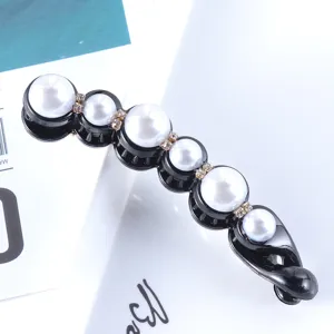 Close-up detail of black banana hair clip with white pearls and rhinestones for styling.