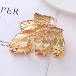 Gold metal leaf hair claw clip close-up, hollow-out plant design for elegant daily hairstyles.