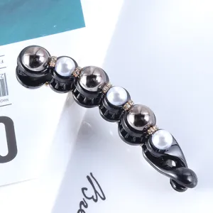 Detail shot of black banana hair clip adorned with pearls, rhinestones and metallic beads.