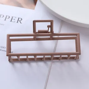 Matte brown metal hair claw clip geometric hollow rectangular hair accessory detail.