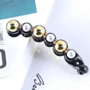 Close-up detail of a Korean style pearl and gold ball banana hair clip with rhinestones.