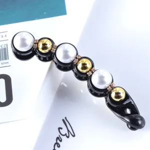 Closeup of elegant pearl and gold ball banana hair clip with sparkling rhinestones.