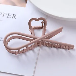 Detail shot of the matte pink metal hair claw clip featuring a cute heart design for daily wear.