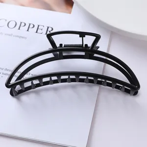 Close-up detail shot of a minimalist black metal hair claw clip showcasing geometric hollow design.