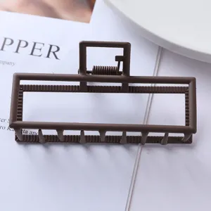 Close-up of the brown matte geometric metal hair claw clip showing hollow frame detail.