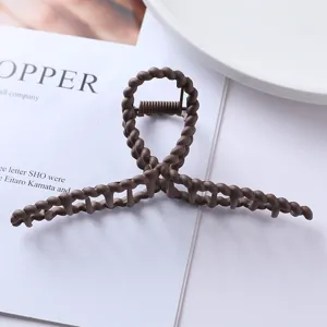 Brown matte hair claw clip detail shot, elegant twisted geometric design for daily hairstyles.