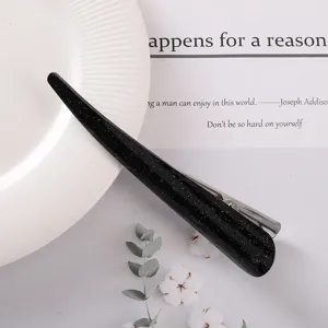 Close-up detail of black glitter acetate hair clip, showing the smooth texture and metal clip.