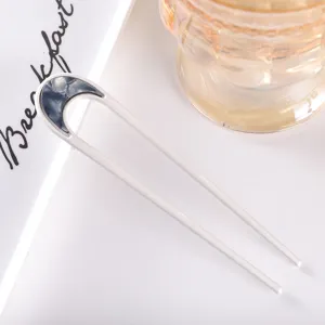 Detailed shot of minimalist U-shaped hairpin with acetate accent on white background.
