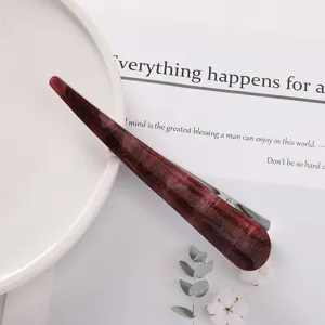 Detail view of the deep red acetate hair clip featuring delicate shimmer and metal clip backend.