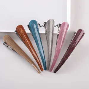 Detailed close-up of colorful curved hair clips in a neat fan arrangement on white tray.