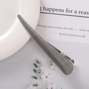 Metal hair clip closeup featuring textured gray surface design, perfect for elegant buns and updos.