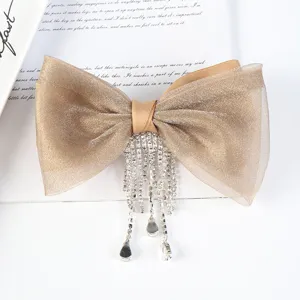 Detail view of the elegant champagne organza bow hair clip featuring shiny rhinestone fringe.