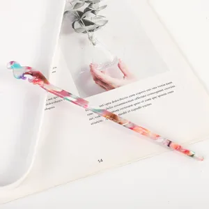 Detail view of a colorful marbled acetate hair stick with traditional hollow carved head.
