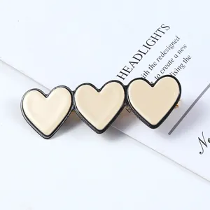 Detail view of Korean style three heart acrylic hair clip, stylish black and beige design.