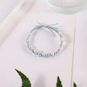 Close-up detail of light blue braided hair rope with elegant pearls and cute bow design.