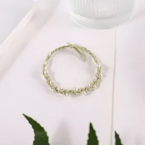 Close-up detail of green braided hair rope with white pearl accents, elegant accessory.