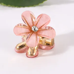 Detailaufnahme einer rosa Blumen Haarklammer mit Strasssteinen und goldenen Metallzähnen.
