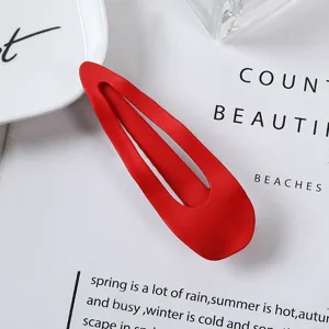 Red teardrop hair clip detail shot, showing matte finish and metal snap clip structure clearly.