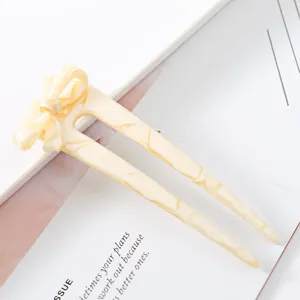 Close-up detail of the elegant acetate U-shaped hair stick featuring a hollow bow design.