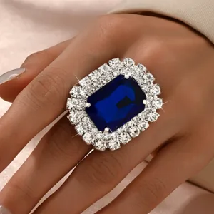 Detailed close-up of a luxury oversized rectangular blue crystal cocktail ring with sparkling rhinestones.