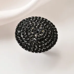Primo piano dettagliato di un grande anello nero in strass con un design geometrico brillante.