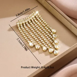 Dettaglio di una spilla con nappe in strass dorati che mostra dimensioni e peso precisi.