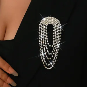 Dettaglio spilla con nappine in strass scintillanti, elegante gioiello con catena multistrato.