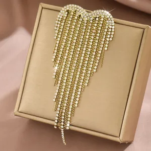 Primo piano dettagliato della spilla con nappe a cuore in strass finitura dorata.