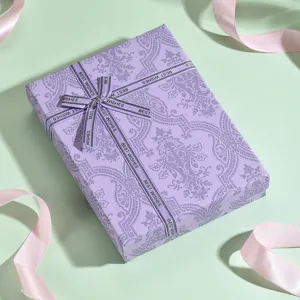Elegante confezione regalo viola con nastro e carta decorata per presentazione di gioielli.