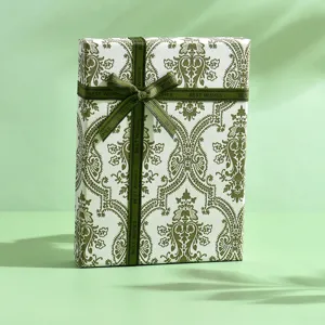 Elegante scatola regalo verde con carta da imballaggio damascata e fiocco in nastro.