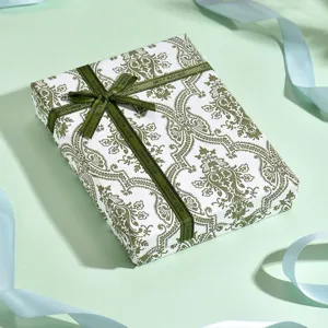 Vista dettagliata di una confezione regalo elegante con carta damascata verde e nastro.