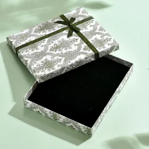 Vista dettagliata dell'elegante scatola regalo per gioielli con fiocco verde e interno in velluto nero.