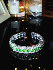 Detailaufnahme eines dreireihigen grünen Strass-offenen Armreifs im Retro-Stil.