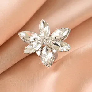 Primo piano di un anello fiore in strass marquise scintillante su sfondo in tessuto setoso.