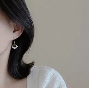 Detailed closeup shot of a delicate dangle earring featuring a green jade bead and mini pearls.