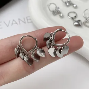 Silver heart hoop earrings detail shot, minimalist chic metal dangle jewelry for women.