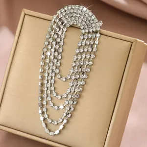 Primo piano dettagliato di una elegante spilla con nappe di strass su scatola dorata.