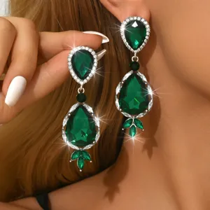 Primo piano dettagliato di orecchini pendenti con cristalli verdi e strass color argento.