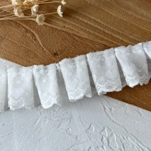 Witte dubbellaagse geplooide kantafwerking in detail, ideaal voor DIY poppenkleding enruffels.