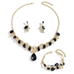 Elegante set di gioielli bagnati d'oro con pietre a goccia nere e foglie di strass scintillanti.
