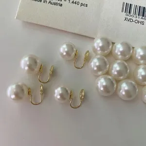Vue détaillée de boucles d'oreilles clips en perles rondes brillantes et dos doré.