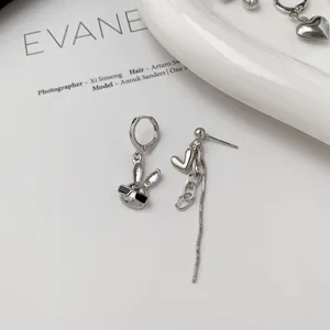 Detail view of asymmetric silver earrings featuring a cute bunny and heart chain tassel.