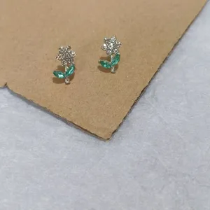 Silver tone floral stud earrings featuring sparkling rhinestones and green leaf crystals.