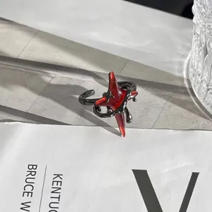 Vista detallada de anillo punk de estrella roja abierta con diseño envuelto negro, nicho.