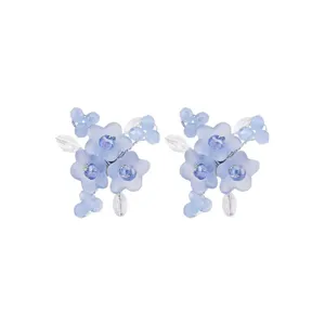 Primo piano di orecchini di perline con fiori blu chiaro, delicati dettagli in cristallo.