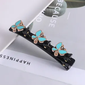 Gedetailleerde close-up van een zwarte dubbellaagse haarklem met turquoise vlinders.