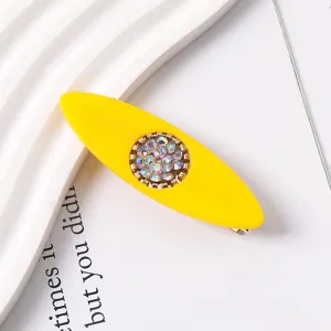 Detailed close-up shot of a vibrant yellow resin hair clip featuring sparkling colorful rhinestones.